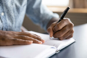 Person writing in notebook with a pen