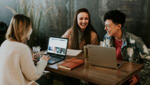 people laughing with laptops at a coffee shop