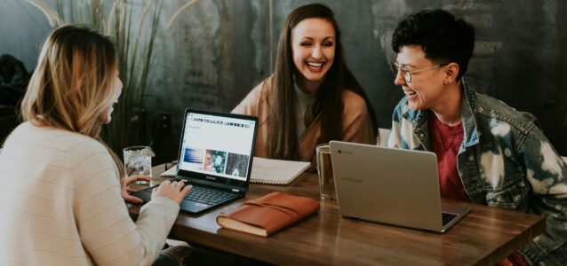 people laughing with laptops at a coffee shop