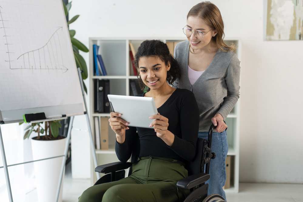 front-view-adult-women-browsing-tablet 1 | Ongig Blog Adult female coworkers, one is using a wheelchair