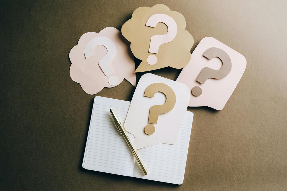 Open notebook with pen below question marks | Ongig Blog Open notebook with pen below question marks