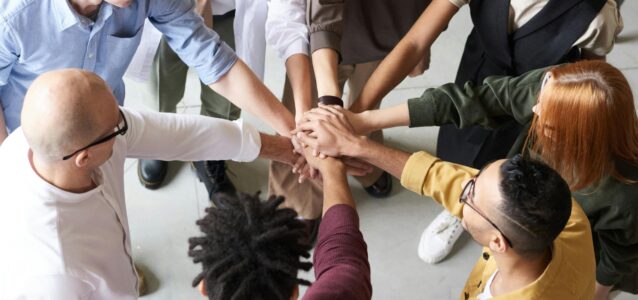 A diverse community of employees engaged in a team huddle.